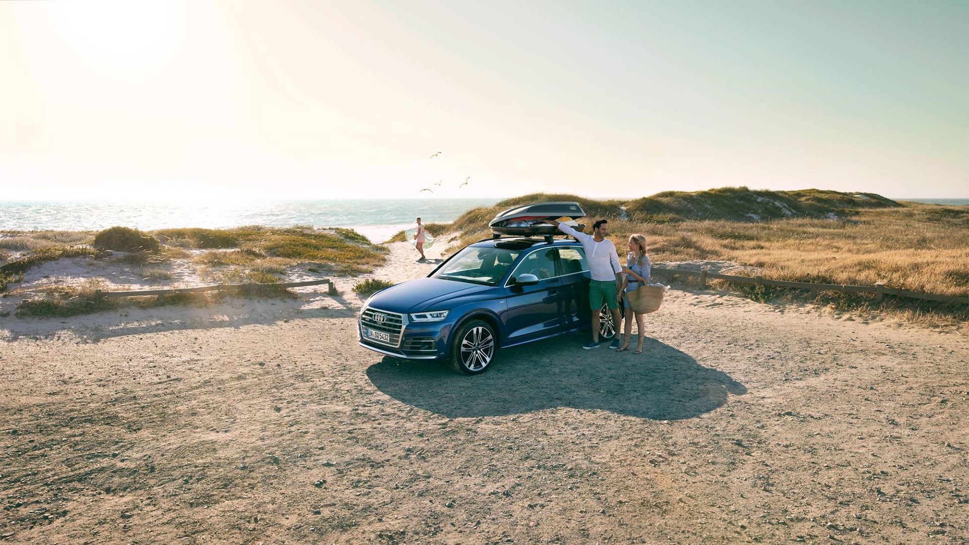 A family with their Audi SQ5 parked on the beach.