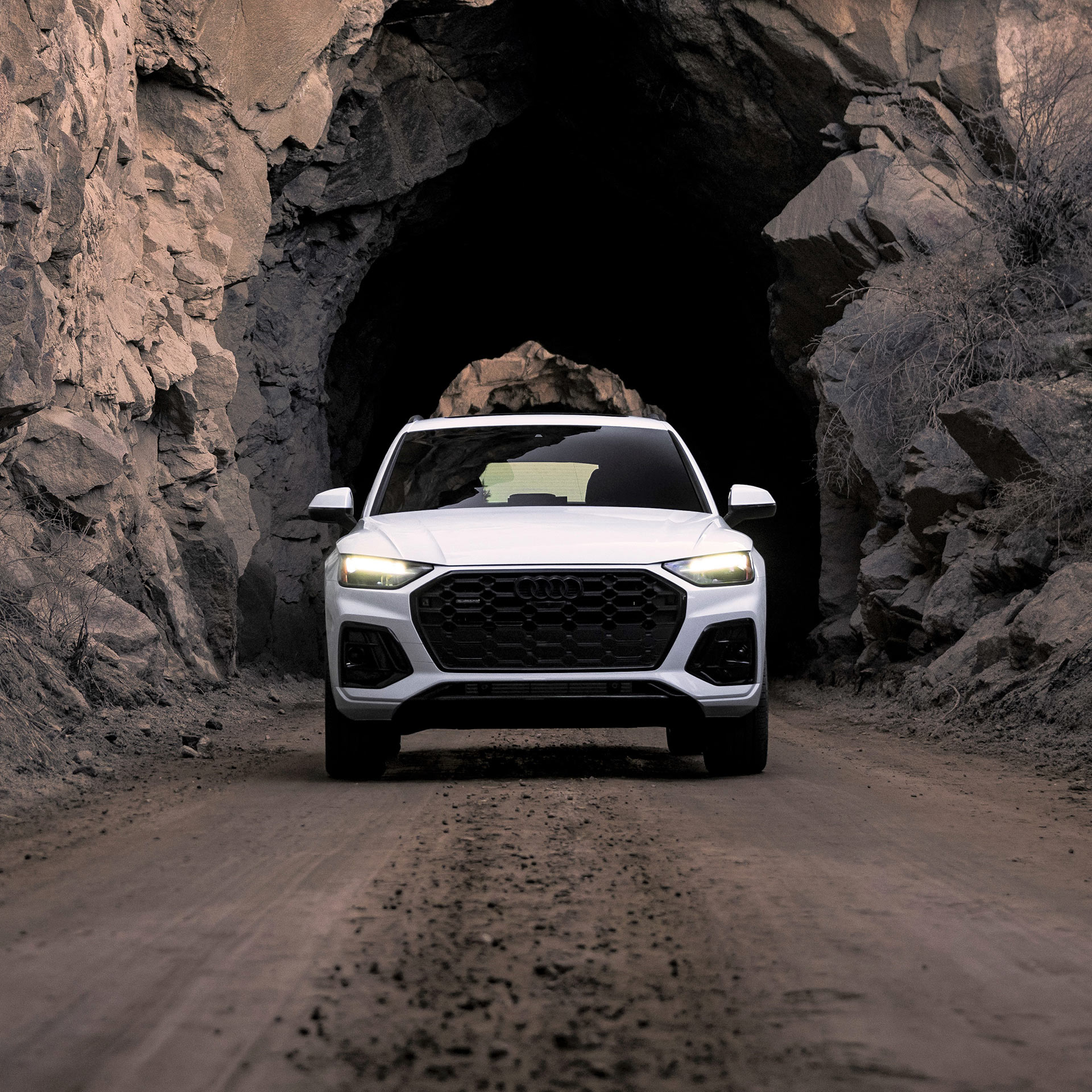 Three-quarter front view of a grey Audi e-tron GT parked with a futuristic city in the background.