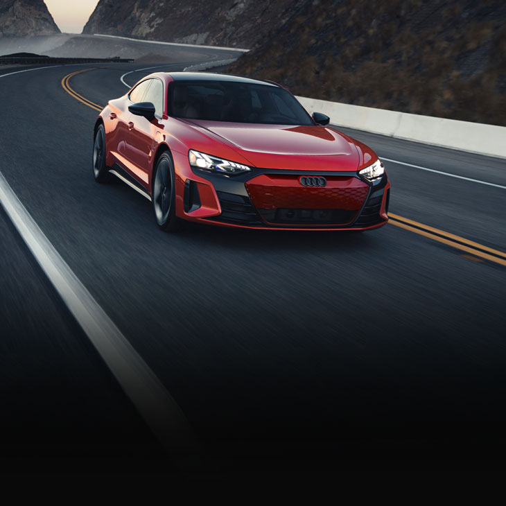 Three-quarter front view of a red Audi RS e-tron GT in motion. 