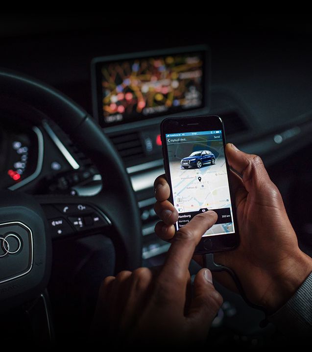 Gros plan d'une personne utilisant l'application myAudi sur son smartphone alors qu'elle est assise dans un véhicule Audi.