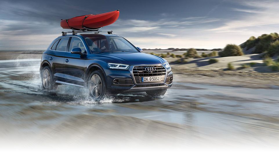 Vue de face d'un véhicule Audi accélérant avec un kayak sur le toit.