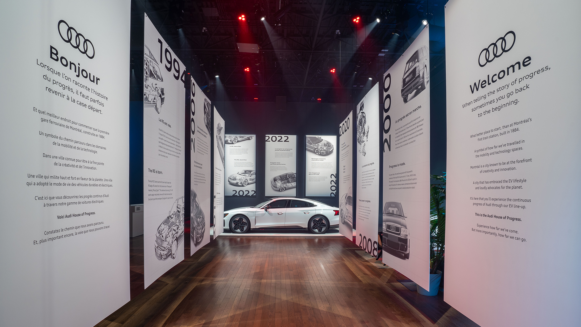 View of a long corridor with the Audi House of Progress installation along the walls, leading towards an Audi vehicle.