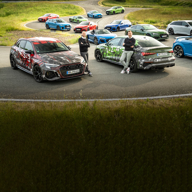 Sebastian Grams and Rolf Michl standing in the middle of a collection of  Audi Sport models. 