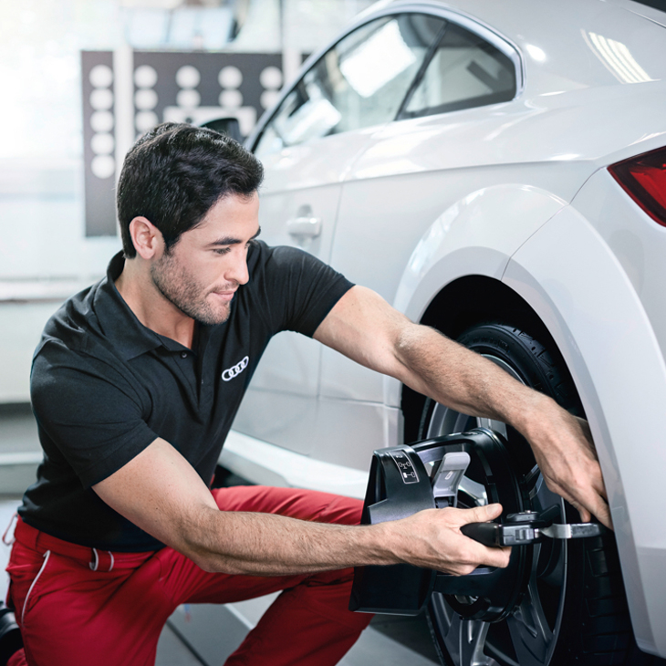 An Audi technician working on the tire of an Audi vehicle. 
