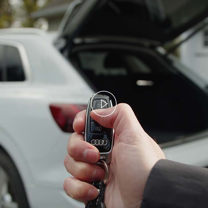 Photo d’une personne utilisant la clé multifonction pour actionner le hayon à commande électrique d’un véhicule Audi. 