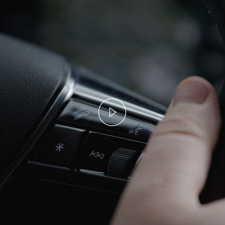 Gros plan du pouce d’une personne appuyant sur le bouton « Talk » du volant multifonction dans un véhicule Audi. 