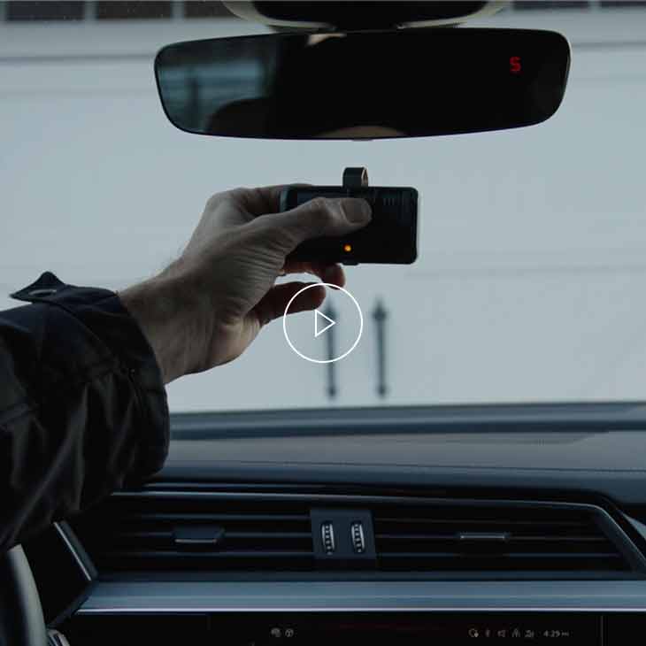 Photo of a person using the hand-held Homelink transmitter to open a garage door.