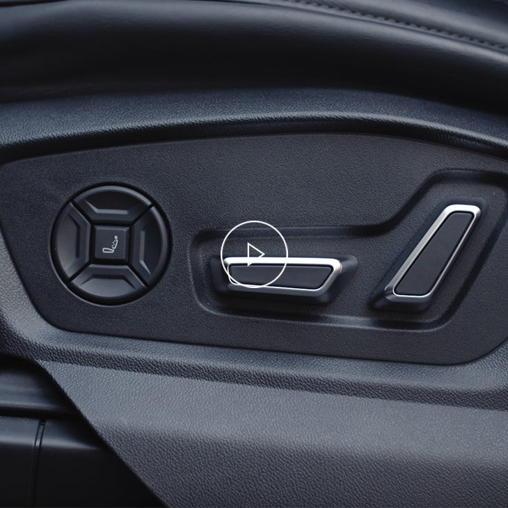 Close-up photo of the front seat adjustment buttons inside an Audi vehicle.