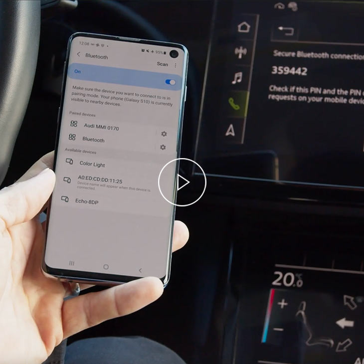  Close-up photo of a person pairing their mobile phone to their Audi vehicle with Bluetooth. 