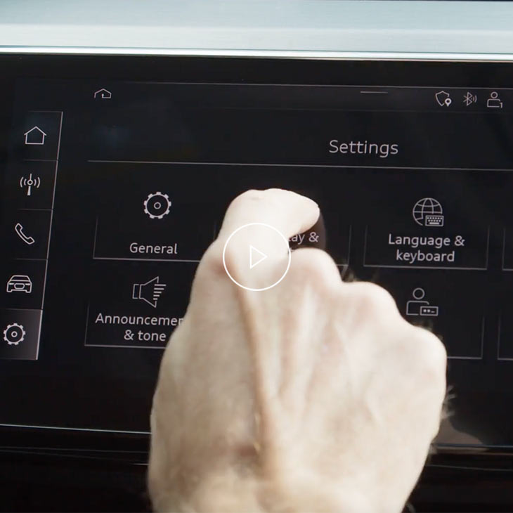 Close-up photo of a person changing the settings of the Audi MMI display inside an Audi vehicle. 