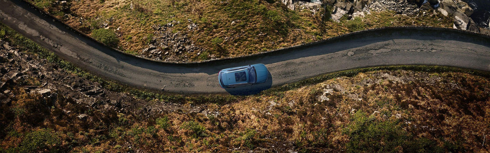 Bird's eye view of an Audi vehicle driving down a winding road. 