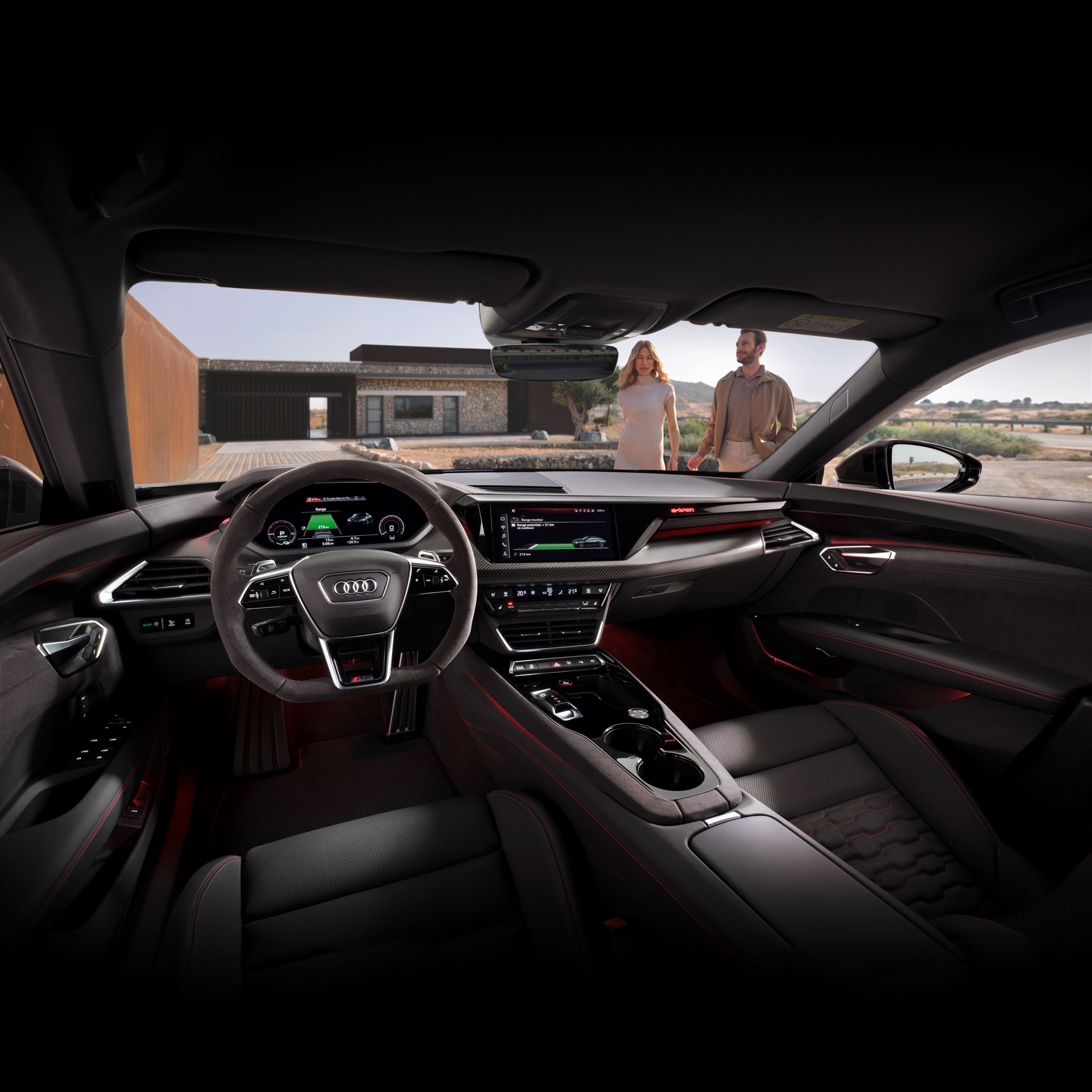 A windshield view of a couple standing outside an Audi from inside the vehicle.