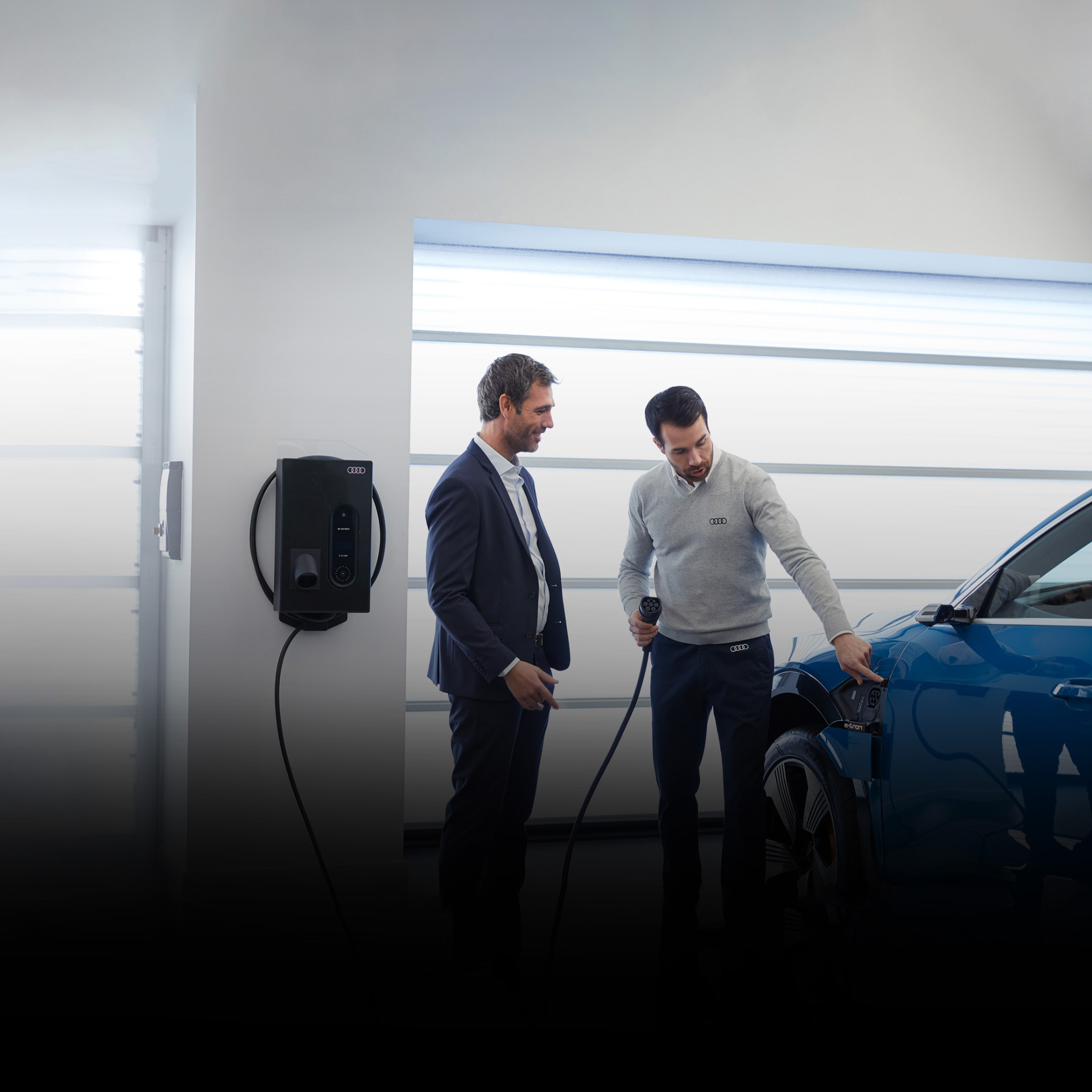 An Audi dealer showing a customer how to charge his Audi e-tron vehicle. 