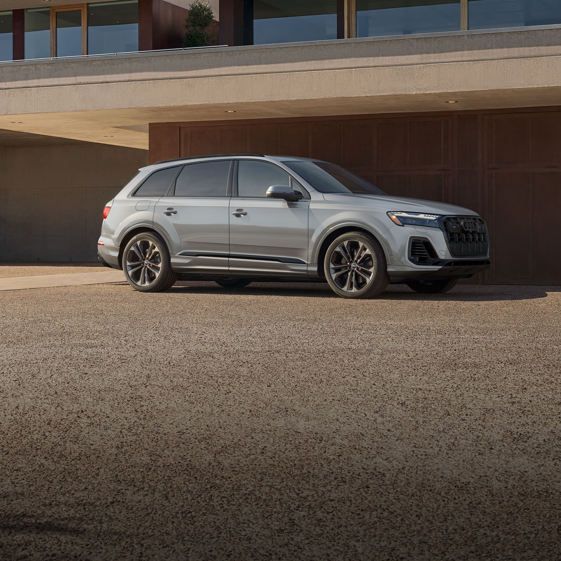 Side profile of the Audi Q7 parked in front of a modern building.